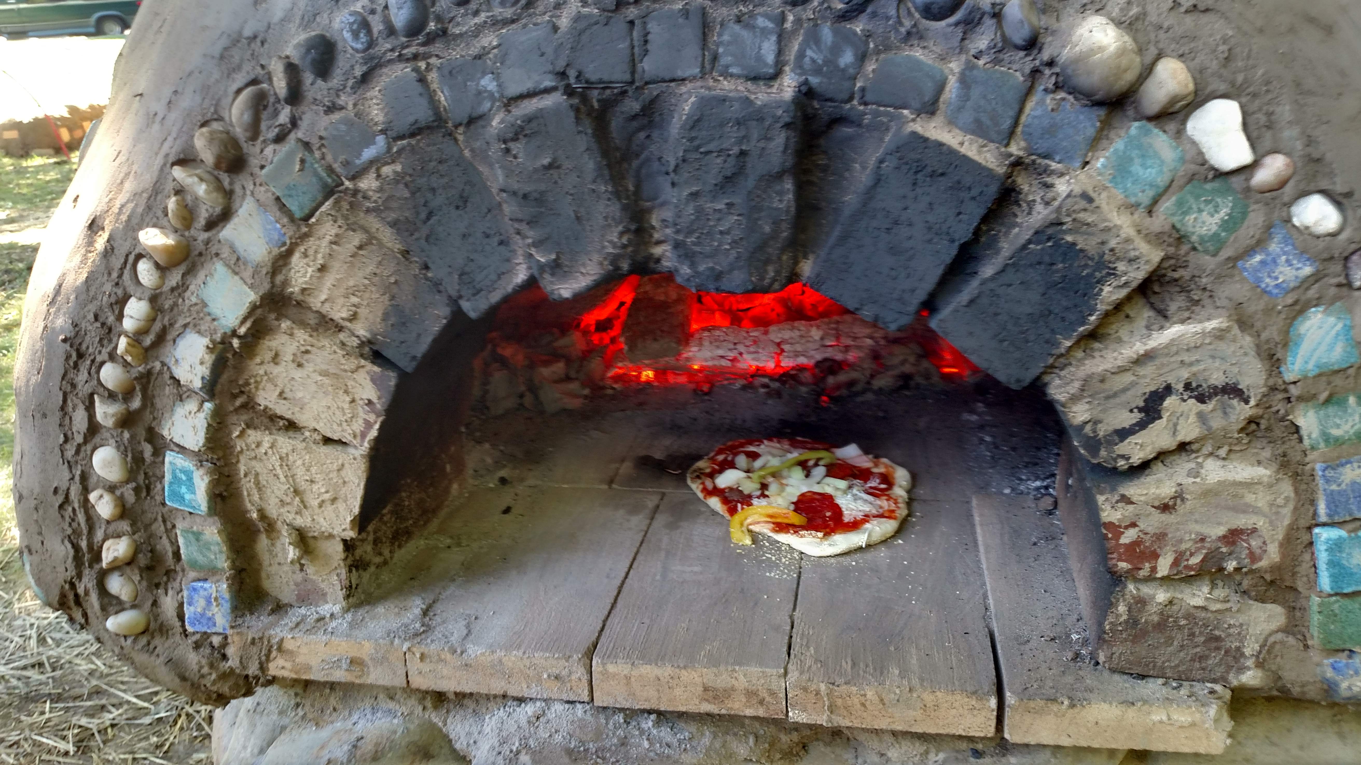 Cooking pizza in the Earthen Cob Oven